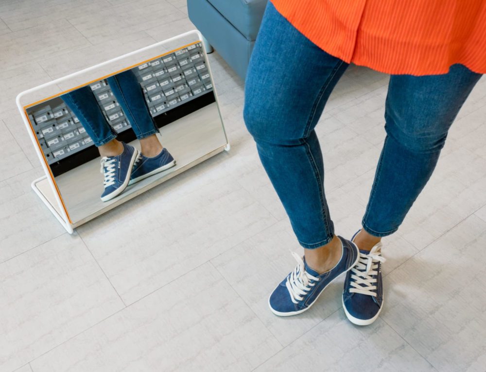 Woman looking at blue canvas shoes in mirror