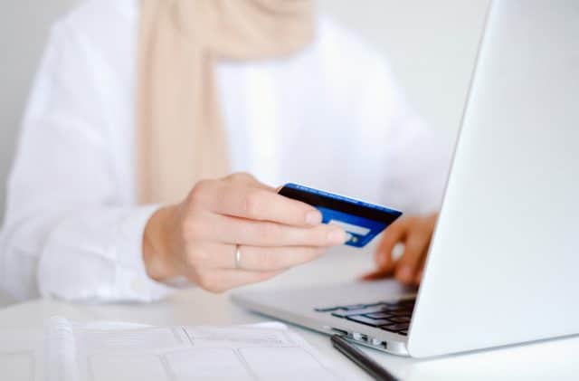 woman at laptop holding credit card
