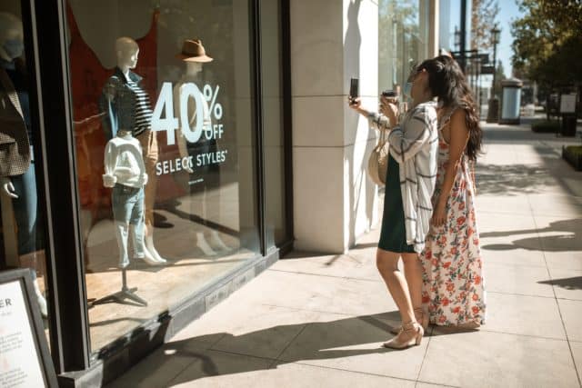 40% off sale sign on store front; two women looking at their phone
