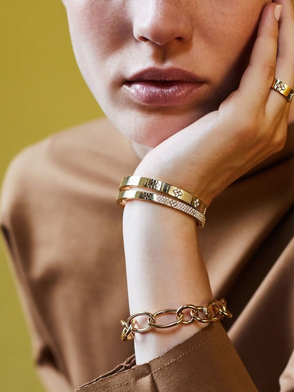 Lux Bond & Green image_ woman wearing multiple gold bracelets and a gold ring