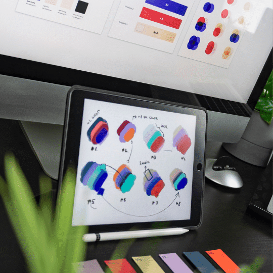 design colors on a computer screen and on an ipad. Colorful notes on a desk